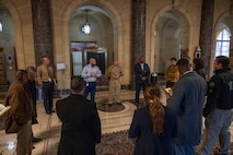 A group of civilians and service members conversing in a hallway of the Capitol building