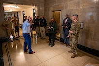 A group of civilians and service members conversing in a hallway of the Capitol building