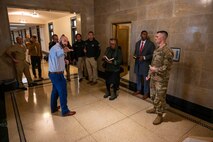 A group of civilians and service members conversing in a hallway of the Capitol building