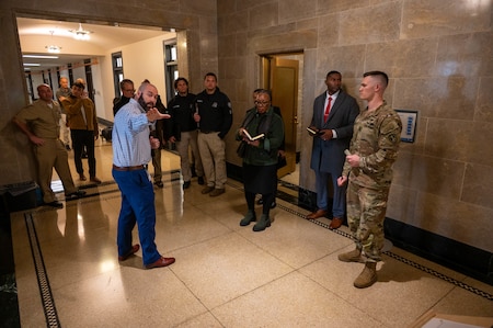 A group of civilians and service members conversing in a hallway of the Capitol building