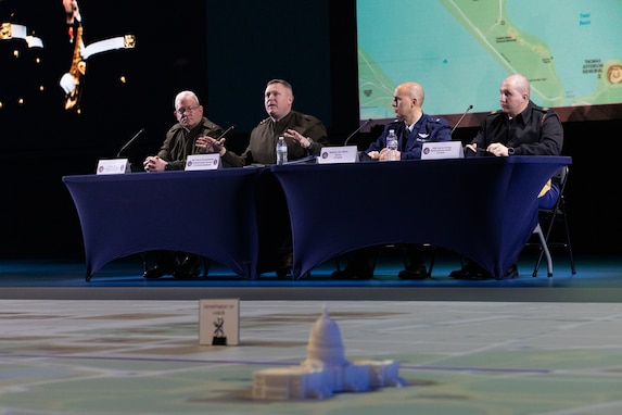 A group of service members lined up at a table responding to media questions from out of frame