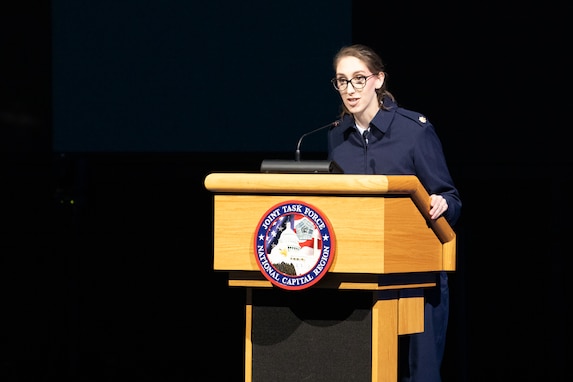 An Airman stands at a lectern while briefing