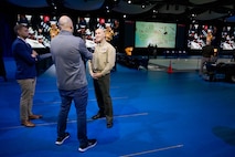 A service member is interviewed by media on a stage.