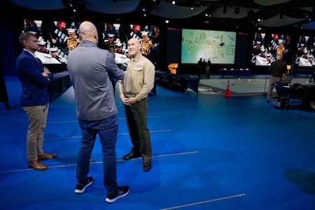 A service member is interviewed by media on a stage.