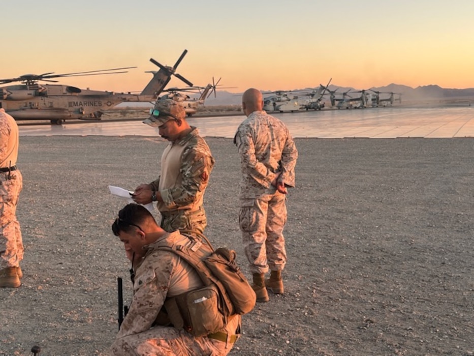 Airmen and Marines working on a flight line with helicopters in the background