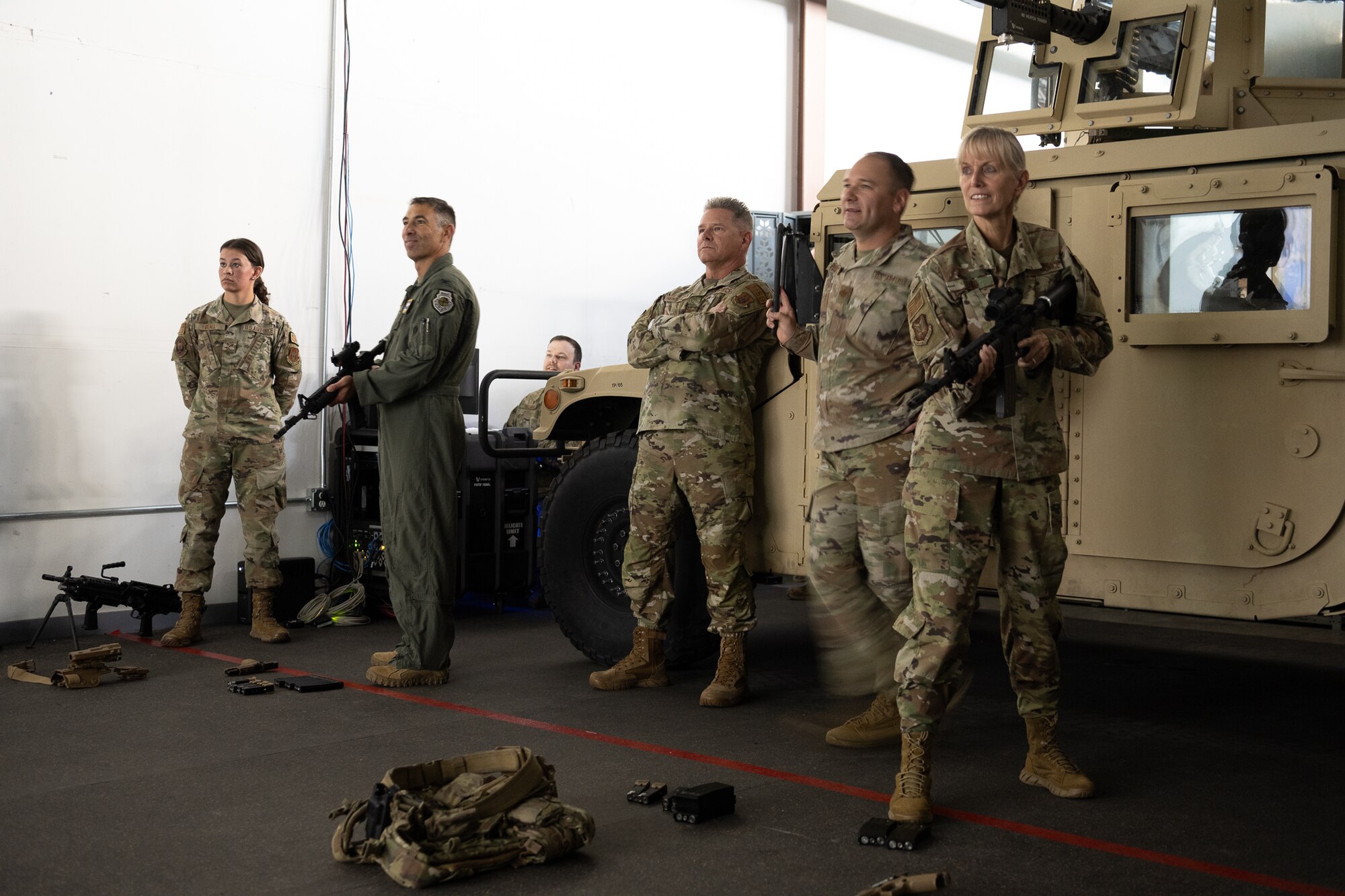 A group of uniformed men and women stare at something off screen with a Humvee parked behind them.