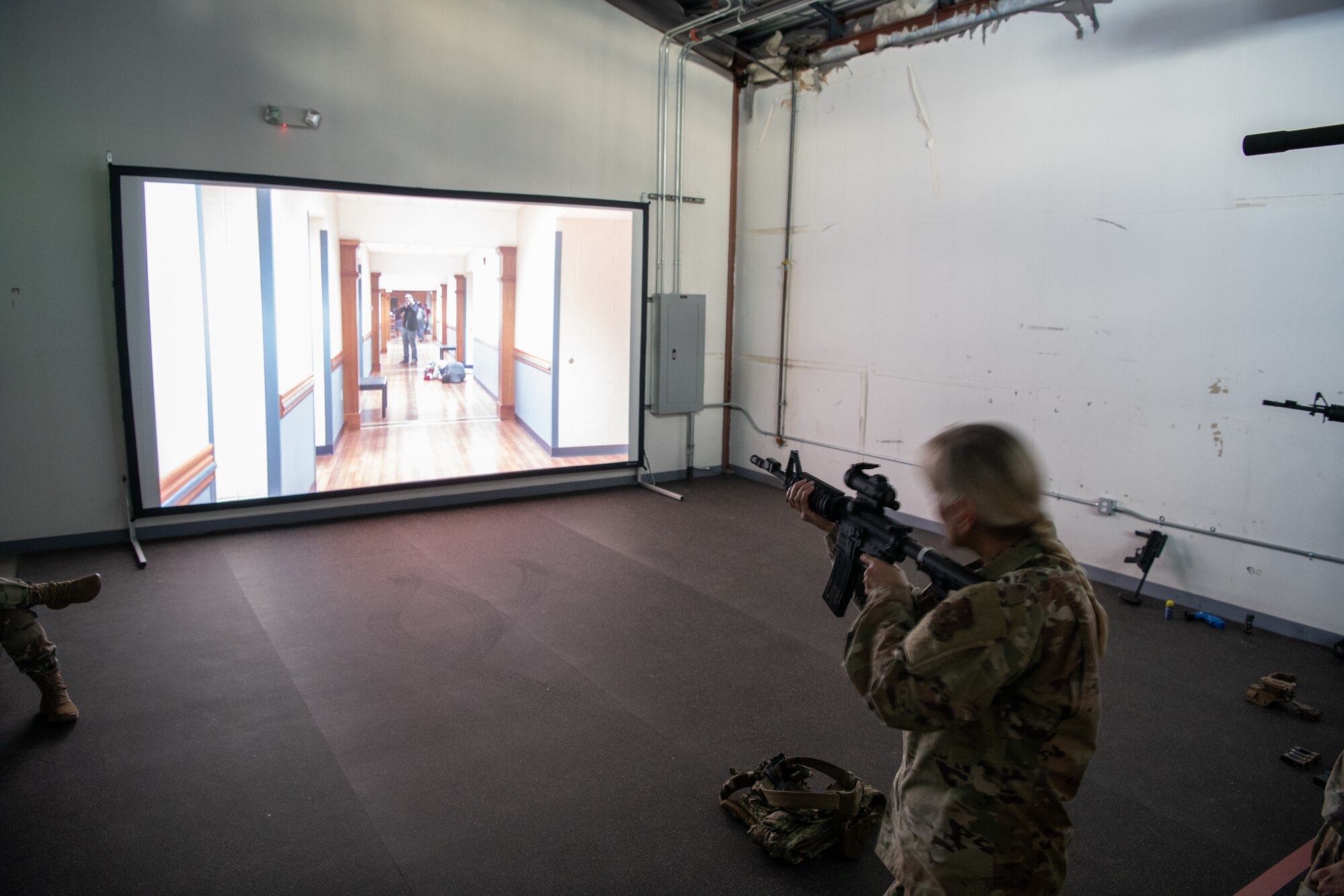 A woman in uniform pointing a rifle at a digital screen.
