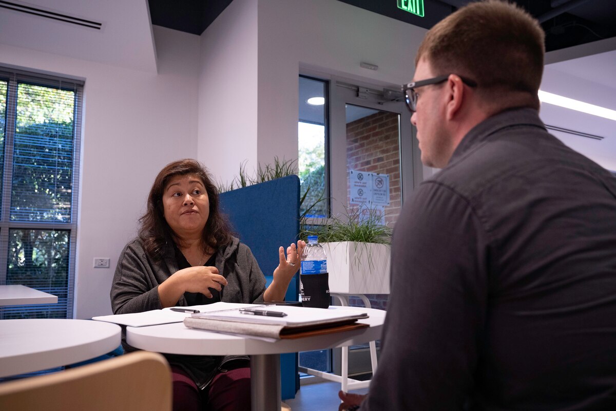 Photo shows man and woman sitting at table talking