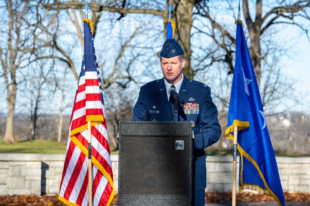 Col. Richards, wearing military service dress delivers remarks at an outdoor ceremony.