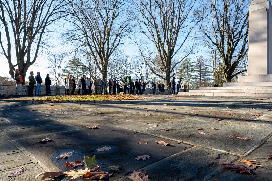 Many individuals gather around the Wright Brothers Memorial during a ceremony.