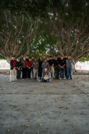 U.S. Marine Corps Mascot of Marine Corps Recruit Depot San Diego and the Western Recruiting Region Lance Cpl. Bruno, poses for a photo with students from John F. Kennedy High School's Marine Corps Junior ROTC program at Marine Corps Recruit Depot San Diego, Dec. 12, 2024. The mascot’s job is to boost morale, participate in outreach work and attend events and ceremonies. (U.S. Marine Corps photo by Cpl. Francisco Angel)
