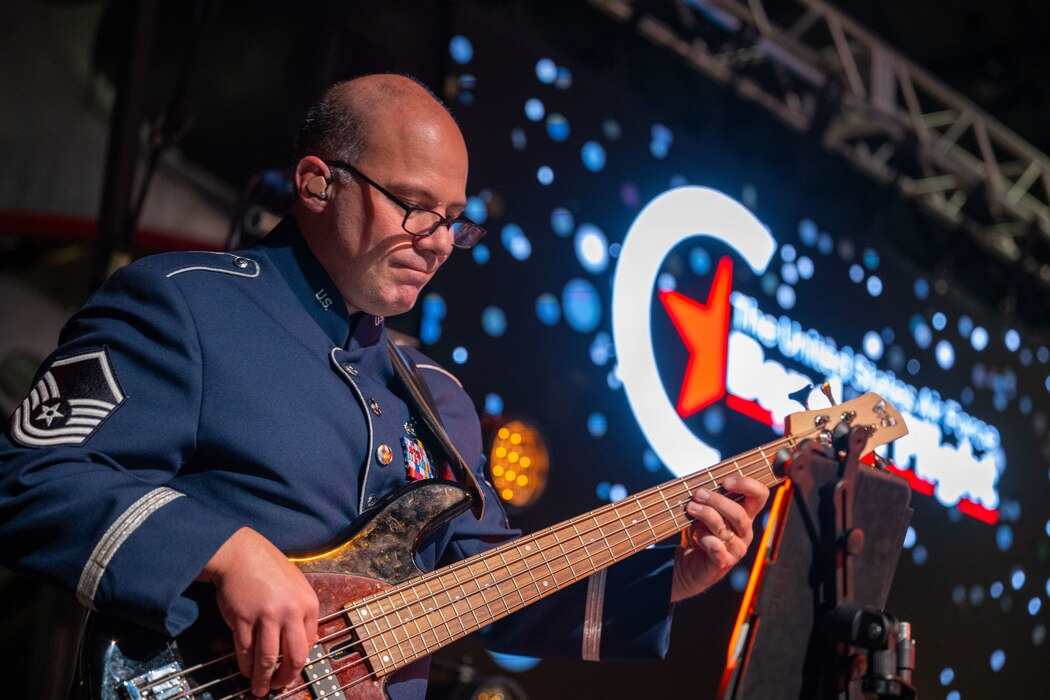 A man wearing a U.S. Air Force service dress uniform plays the bass during a holiday concert.