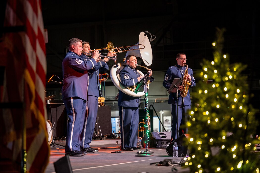Air Force military brass band members perform on stage during a holiday concert.