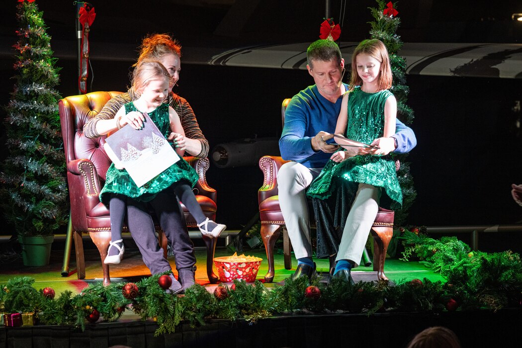 Col. Richards, his wife and two daughters sit on stage preparing to read a story during a holiday concert.