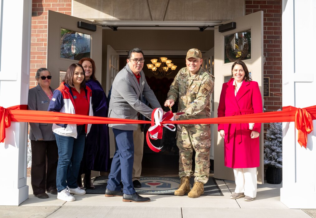 Many individuals cut a red ribbon outside of Fisher House I on Wright-Patterson Air Force Base, Ohio.