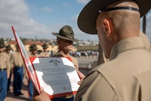U.S. Marine Corps 1st Recruit Training Battalion Sergeant Major, Sgt. Maj. Jonathan Meja, with Marine Corps Recruit Depot San Diego, reads the warrant for Drill Instructor, Staff Sgt. Barry Clayton, back right, with Charlie Company, 1st Recruit Training Battalion, who is being presented with a Navy and Marine Corps Achievement Medal at MCRD San Diego, California, Dec. 13, 2024. A NAM is given to members of the U.S. Navy and Marine Corps for meritorious service or achievement. Delacruz and Clayton received a NAM for exemplifying unrivaled courage and extraordinary presence of mind when confronting a life-threatening emergency. The words “drill instructor, drill instructor, drill instructor” were called and Delacruz and Clayton sprang into action to save a fourteen-month-old infant who was unconscious and not breathing. Providing CPR and proper throat sweeping techniques they successfully dislodged the obstruction and the infant regained consciousness. Likely saving baby Aisla’s life.  The family of the infant was onsite during the ceremony and presented the awards. The Marine Corps has served the Nation honorably for 250 years. Marines embody the uncompromising standards and characteristics of honor, courage and commitment.