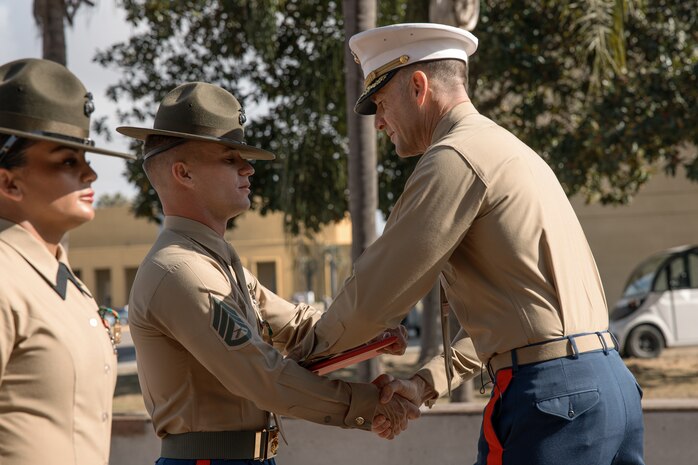 U.S. Marine Corps Drill Instructor, Staff Sgt. Barry Clayton with Charlie Company, 1st Recruit Training Battalion, is presented with a Navy and Marine Corps Achievement Medal from Commanding Officer of 1st Recruit Training Battalion, Lt. Col. Roger Hollenbeck, Marine Corps Recruit Depot San Diego at MCRD San Diego, California, Dec. 13, 2024. A NAM is given to members of the U.S. Navy and Marine Corps for meritorious service or achievement. Delacruz and Clayton received a NAM for exemplifying unrivaled courage and extraordinary presence of mind when confronting a life-threatening emergency. The words “drill instructor, drill instructor, drill instructor” were called and Delacruz and Clayton sprang into action to save a fourteen-month-old infant who was unconscious and not breathing. Providing CPR and proper throat sweeping techniques they successfully dislodged the obstruction and the infant regained consciousness. Likely saving baby Aisla’s life.  The family of the infant was onsite during the ceremony and presented the awards. The Marine Corps has served the Nation honorably for 250 years. Marines embody the uncompromising standards and characteristics of honor, courage and commitment.