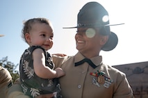 Baby Aisla interacts with U.S. Marine Corps Drill Instructor, Staff Sgt. Burruel Delacruz, left, with Charlie Company, 1st Recruit Training Battalion, after being presented with a Navy and Marine Corps Achievement Medal at Marine Corps Recruit Depot San Diego, California, Dec. 13, 2024. A NAM is given to members of the U.S. Navy and Marine Corps for meritorious service or achievement. Delacruz and Clayton received a NAM for exemplifying unrivaled courage and extraordinary presence of mind when confronting a life-threatening emergency. The words “drill instructor, drill instructor, drill instructor” were called and Delacruz and Clayton sprang into action to save a fourteen-month-old infant who was unconscious and not breathing. Providing CPR and proper throat sweeping techniques they successfully dislodged the obstruction and the infant regained consciousness. Likely saving baby Aisla’s life.  The family of the infant was onsite during the ceremony and presented the awards. The Marine Corps has served the Nation honorably for 250 years. Marines embody the uncompromising standards and characteristics of honor, courage and commitment.