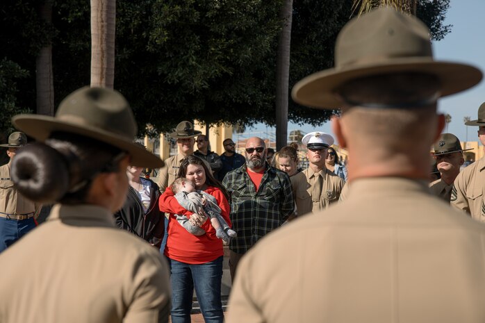 The family of baby Aisla observes U.S. Marine Corps Drill Instructors, Staff Sgt. Burruel Delacruz, front left, and Staff Sgt. Barry Clayton, back left, both with Charlie Company, 1st Recruit Training Battalion, are presented a Navy and Marine Corps Achievement Medal at Marine Corps Recruit Depot San Diego, California, Dec. 13, 2024. A NAM is given to members of the U.S. Navy and Marine Corps for meritorious service or achievement. Delacruz and Clayton received a NAM for exemplifying unrivaled courage and extraordinary presence of mind when confronting a life-threatening emergency. The words “drill instructor, drill instructor, drill instructor” were called and Delacruz and Clayton sprang into action to save a fourteen-month-old infant who was unconscious and not breathing. Providing CPR and proper throat sweeping techniques they successfully dislodged the obstruction and the infant regained consciousness. Likely saving baby Aisla’s life.  The family of the infant was onsite during the ceremony and presented the awards. The Marine Corps has served the Nation honorably for 250 years. Marines embody the uncompromising standards and characteristics of honor, courage and commitment.