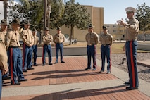 U.S. Marine Corps Commanding Officer of 1st Recruit Training Battalion, Lt. Col. Roger Hollenbeck, right, Marine Corps Recruit Depot San Diego, speaks about Drill Instructors, Staff Sgt. Barry Clayton and Staff Sgt. Burruel Delacruz, both with Charlie Company, 1st Recruit Training Battalion, for being presented with a Navy and Marine Corps Achievement Medal at MCRD San Diego, California, Dec. 13, 2024. A NAM is given to members of the U.S. Navy and Marine Corps for meritorious service or achievement. Delacruz and Clayton received a NAM for exemplifying unrivaled courage and extraordinary presence of mind when confronting a life-threatening emergency. The words “drill instructor, drill instructor, drill instructor” were called and Delacruz and Clayton sprang into action to save a fourteen-month-old infant who was unconscious and not breathing. Providing CPR and proper throat sweeping techniques they successfully dislodged the obstruction and the infant regained consciousness. Likely saving baby Aisla’s life.  The family of the infant was onsite during the ceremony and presented the awards. The Marine Corps has served the Nation honorably for 250 years. Marines embody the uncompromising standards and characteristics of honor, courage and commitment.