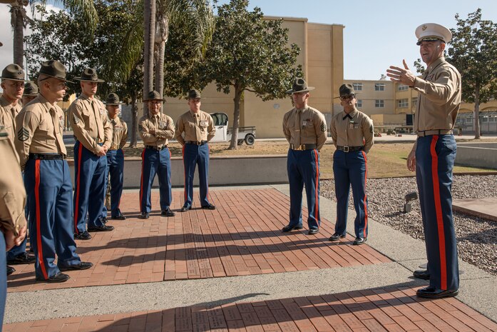 U.S. Marine Corps Commanding Officer of 1st Recruit Training Battalion, Lt. Col. Roger Hollenbeck, right, Marine Corps Recruit Depot San Diego, speaks about Drill Instructors, Staff Sgt. Barry Clayton and Staff Sgt. Burruel Delacruz, both with Charlie Company, 1st Recruit Training Battalion, for being presented with a Navy and Marine Corps Achievement Medal at MCRD San Diego, California, Dec. 13, 2024. A NAM is given to members of the U.S. Navy and Marine Corps for meritorious service or achievement. Delacruz and Clayton received a NAM for exemplifying unrivaled courage and extraordinary presence of mind when confronting a life-threatening emergency. The words “drill instructor, drill instructor, drill instructor” were called and Delacruz and Clayton sprang into action to save a fourteen-month-old infant who was unconscious and not breathing. Providing CPR and proper throat sweeping techniques they successfully dislodged the obstruction and the infant regained consciousness. Likely saving baby Aisla’s life.  The family of the infant was onsite during the ceremony and presented the awards. The Marine Corps has served the Nation honorably for 250 years. Marines embody the uncompromising standards and characteristics of honor, courage and commitment.