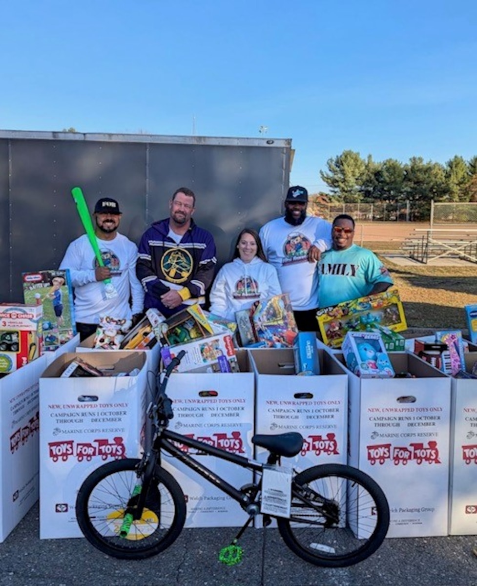 Participants stand in front of boxes of toys for donation.