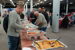 People serve themselves food from a buffet.