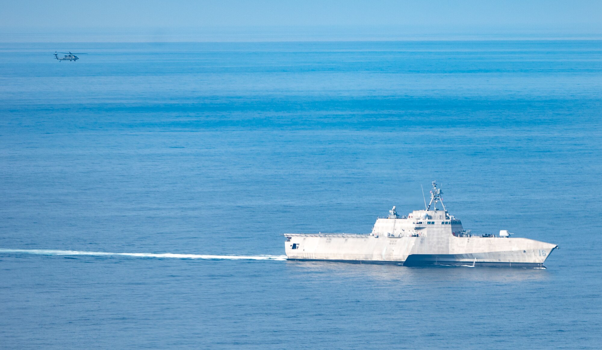 A U.S. Air Force HH-60W Jolly Green II helicopter approaches littoral combat ship USS Tulsa (LCS 16)