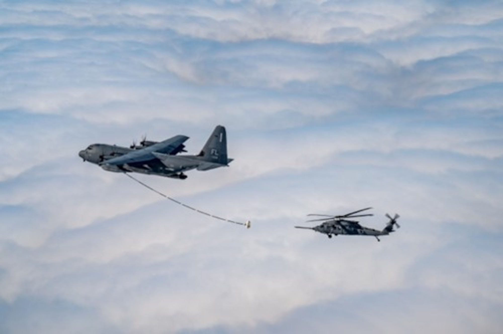 A U.S. Air Force HH-60W Jolly Green II helicopter approaches an HC-130J Combat King II aircraft