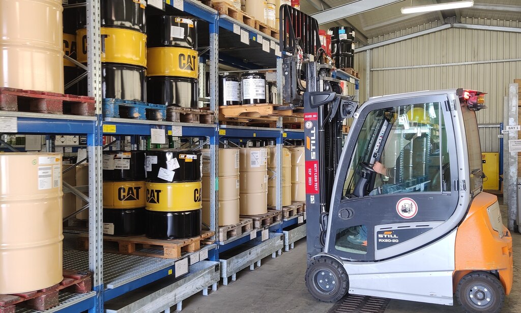 A forklift driver uses a forklift to move barrels of HAZMAT.