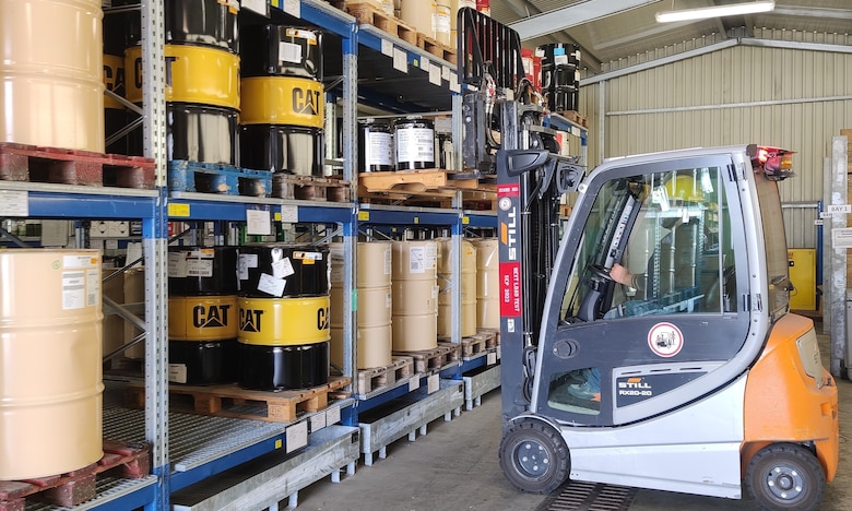 A forklift driver uses a forklift to move barrels of HAZMAT.