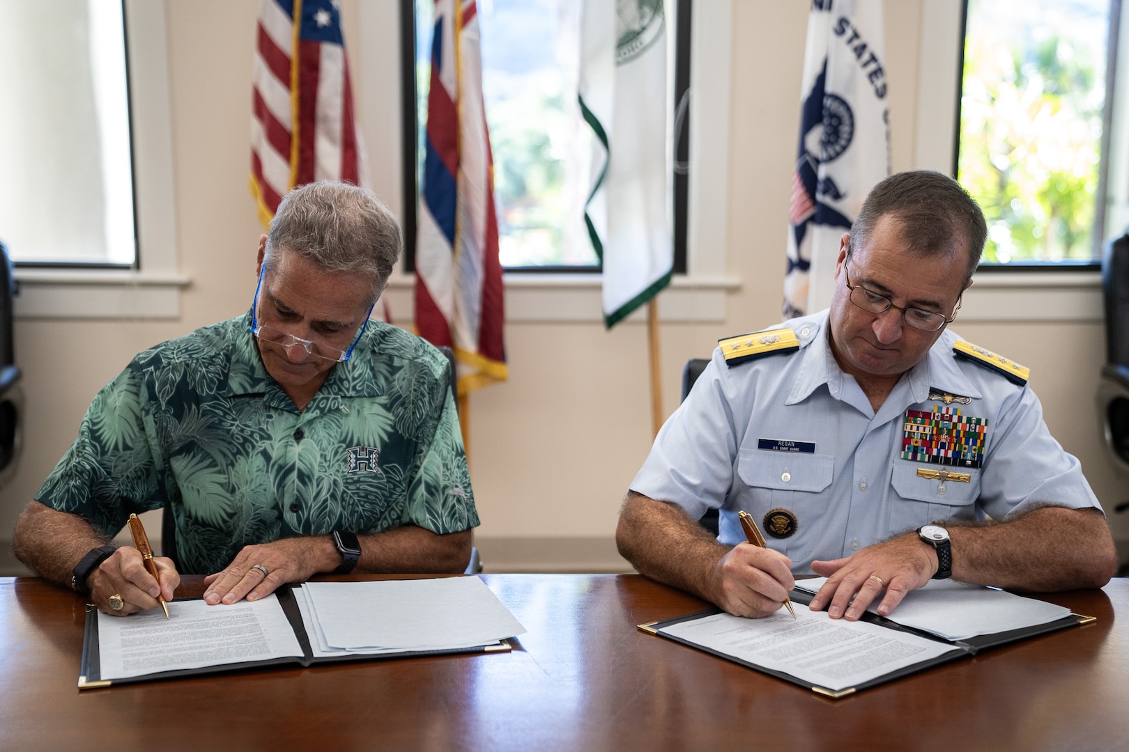 Coast Guard Rear Adm. Sean Regan, commander of District Fourteen, and Michael Bruno, provost at the University of Hawai’i at Mānoa, sign an updated memorandum of agreement to continue the College Student Pre-Commissioning Initiative scholarship program at UH Mānoa in Honolulu, Hawaii, Dec. 19, 2024. The Coast Guard CSPI program pays for up to two academic years of college tuition for eligible students at minority-serving institutions. (U.S. Coast Guard photo by Petty Officer 2nd Class Tyler Robertson)