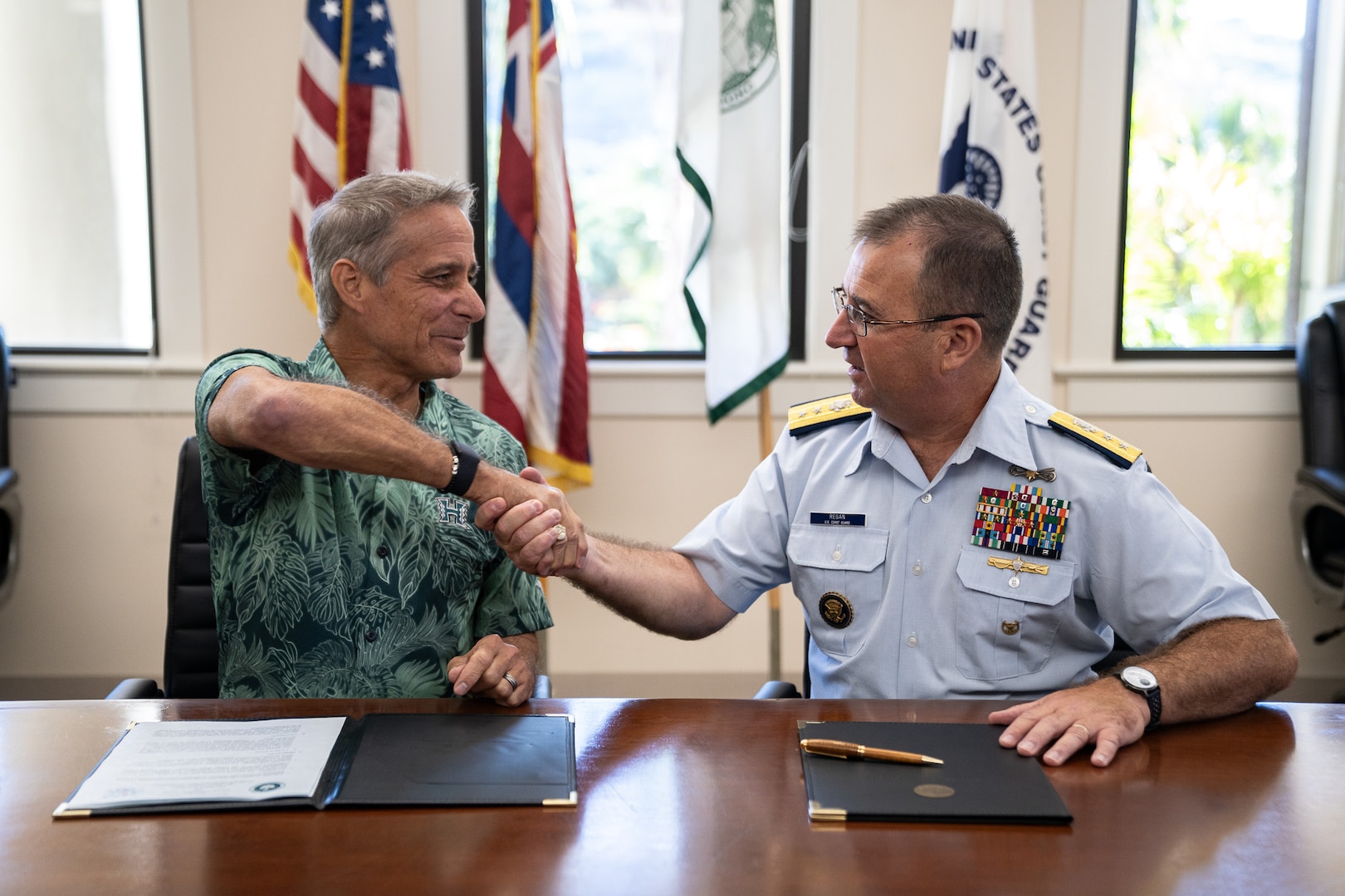 Coast Guard Rear Adm. Sean Regan, commander of District Fourteen, and Michael Bruno, provost at the University of Hawai’i at Mānoa, shake hands after signing an updated memorandum of agreement during a ceremony at UH Mānoa in Honolulu, Hawaii, Dec. 19, 2024. The Coast Guard CSPI program pays for up to two academic years of college tuition for eligible students at minority-serving institutions. (U.S. Coast Guard photo by Petty Officer 2nd Class Tyler Robertson)