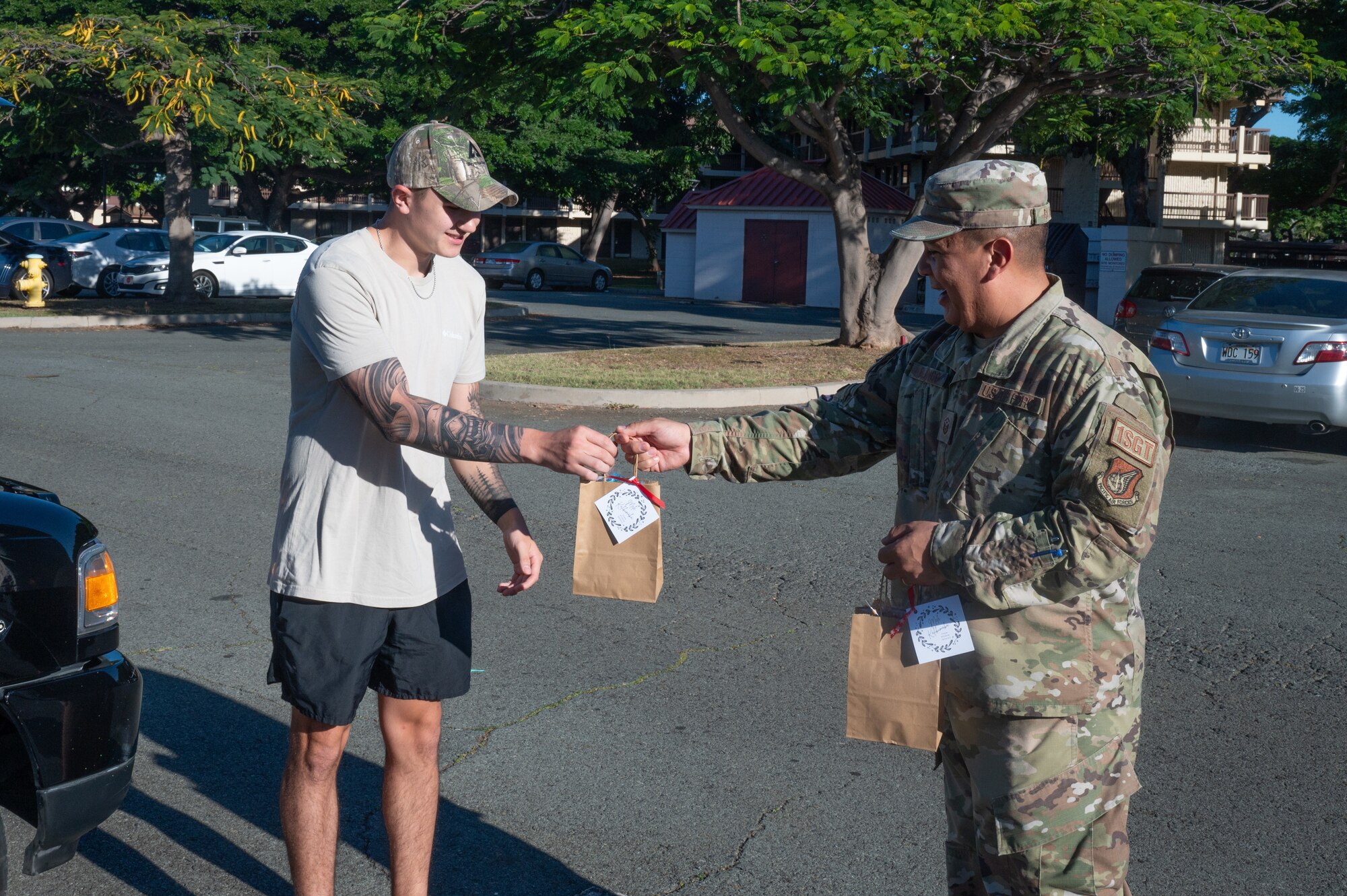 a man grabs a bag from an Airman at a parking lot for a cookie caper drop off.