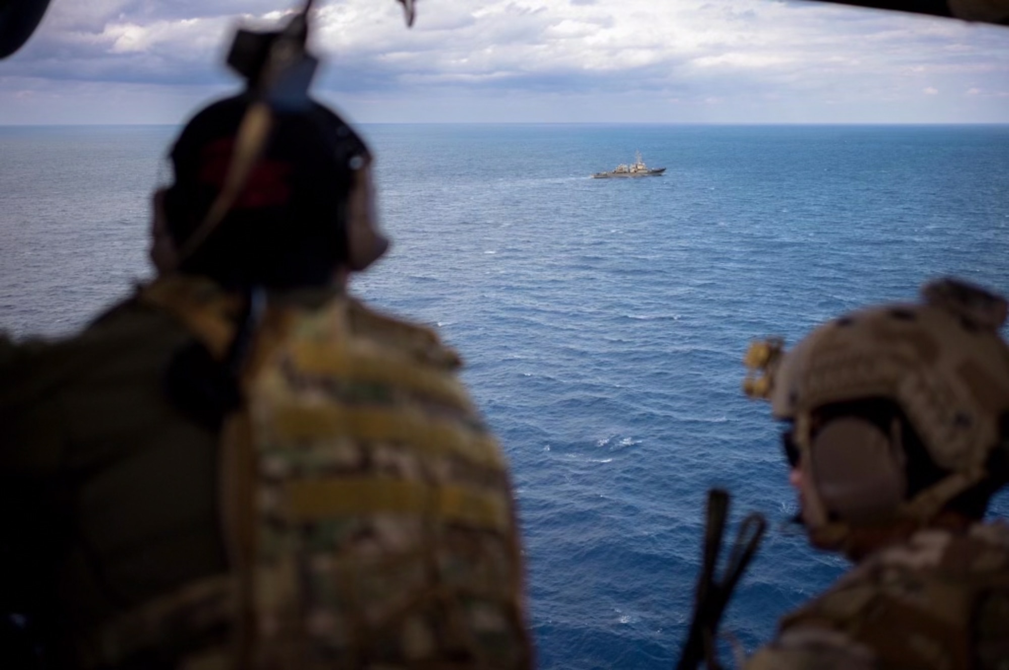 Service members looking at a boat from a helicopter view.