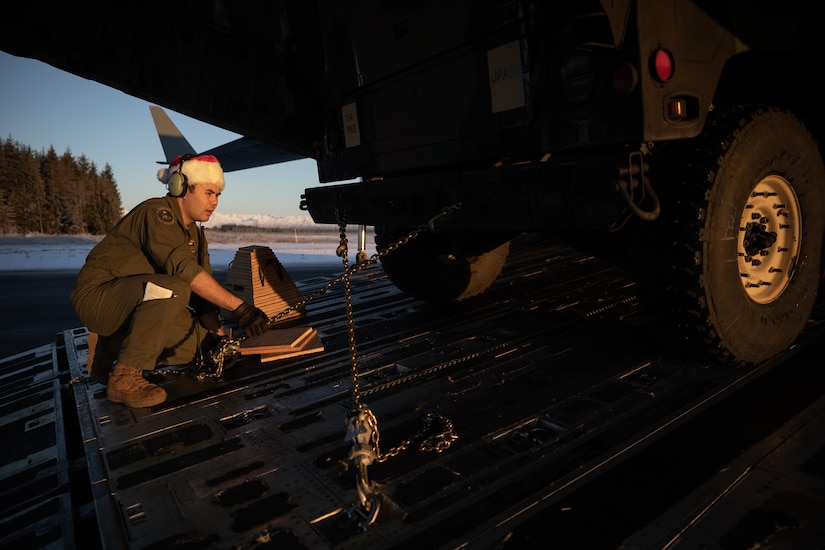 Alaska Air National Guard Airman 1st Class Trystan Costanios, a loadmaster assigned to the 144th Airlift Squadron, 176th Wing, secures an Alaska Army National Guard Humvee onto a C-17 Globemaster III in support of Operation Santa Claus at Yakutat, Alaska, Dec. 18, 2024.