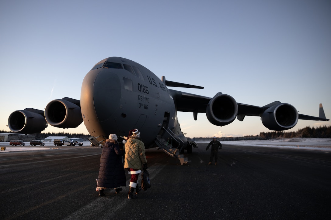 Mr. and Mrs. Claus make their way to an Alaska Air National Guard C-17 Globemaster III, belonging to the 144th Airlift Squadron, 176th Wing, as they prepare to depart Yakutat, Alaska, after completing Operation Santa Claus, Dec. 18, 2024.