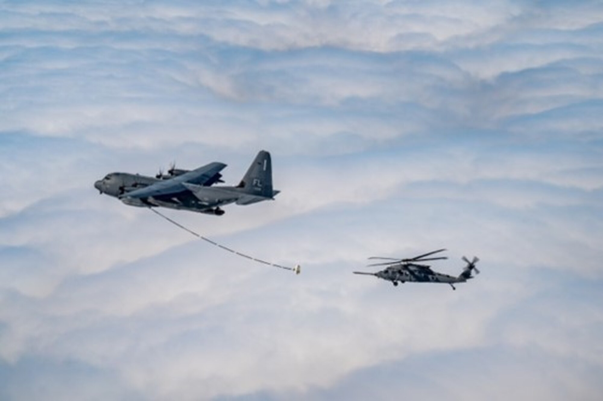 A U.S. Air Force HH-60W Jolly Green II helicopter approaches an HC-130J Combat King II aircraft
