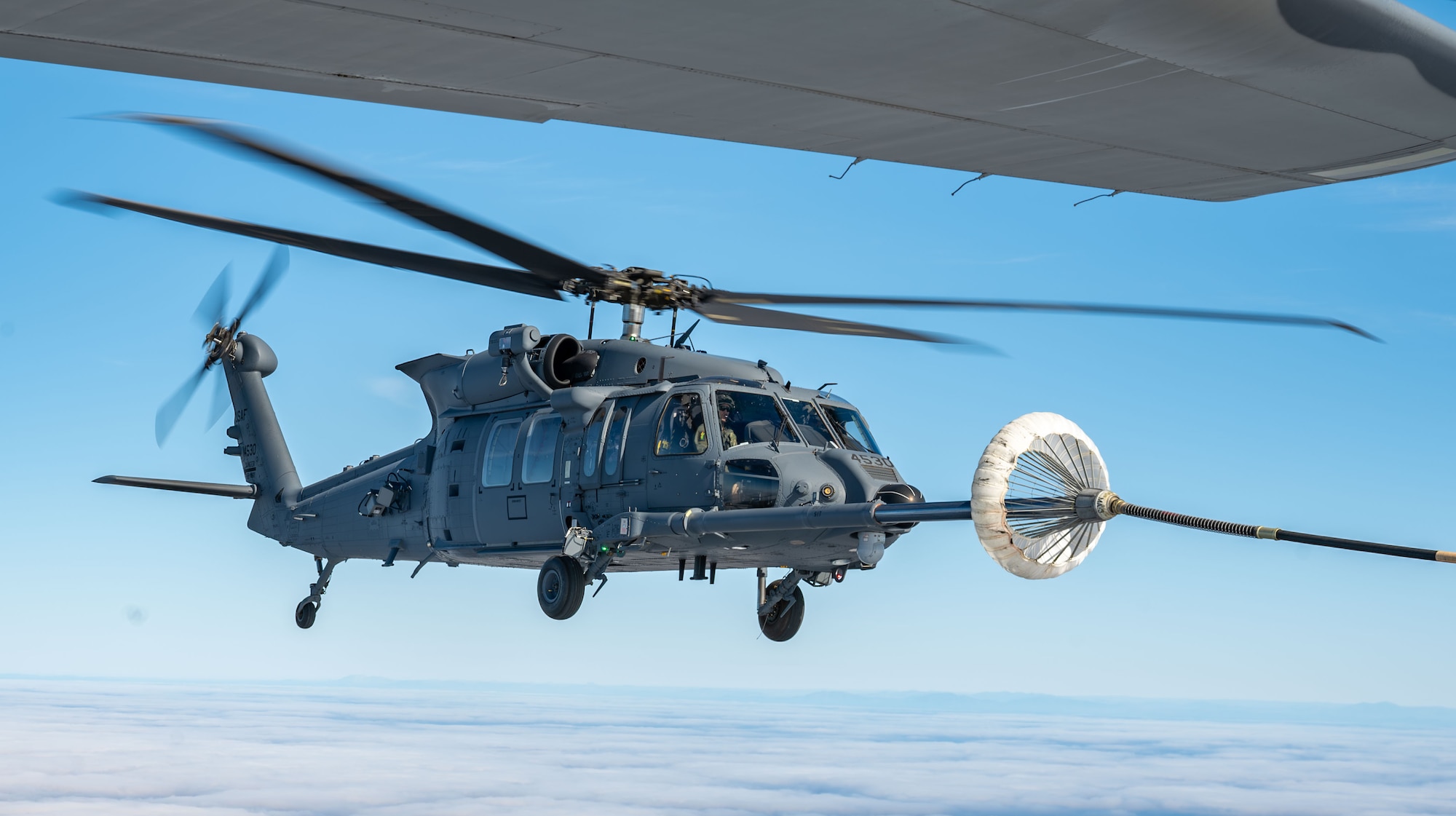 A U.S. Air Force HH-60W Jolly Green II helicopter receives fuel from an HC-130J Combat King II aircraft