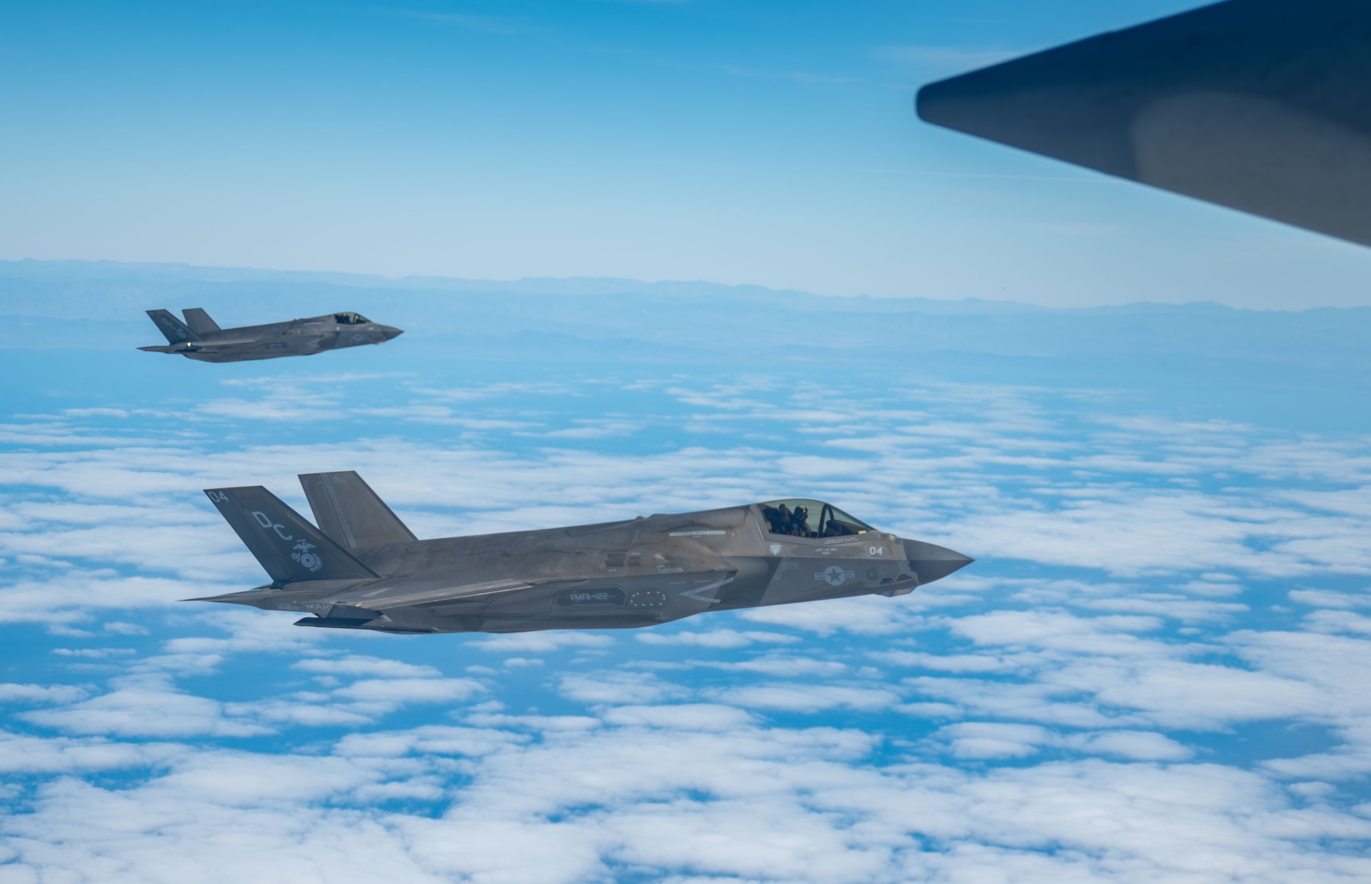 U.S. Marine Corps F-35B Lightning II aircraft fly alongside an HC-130J Combat King II aircraft