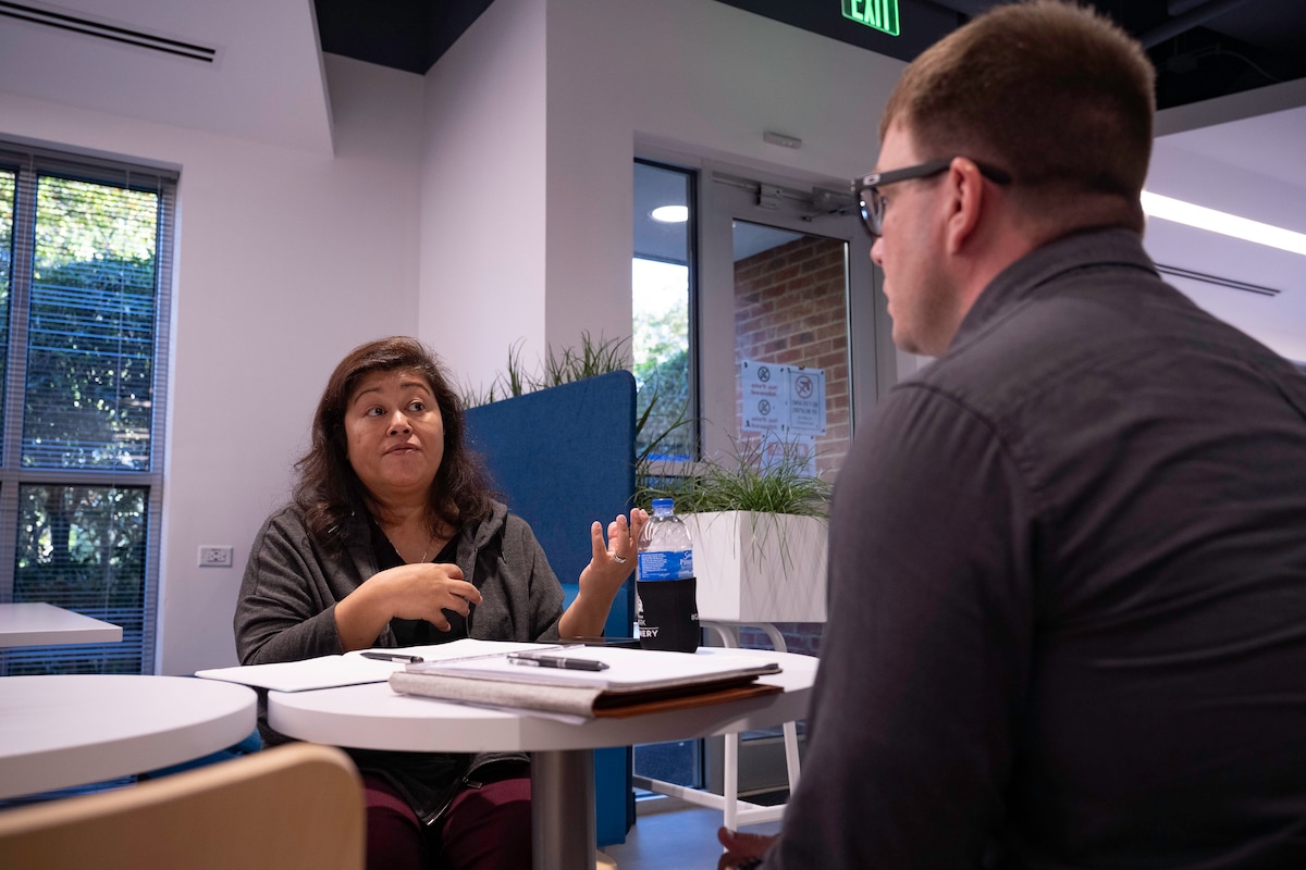 Photo shows man and woman sitting at table talking