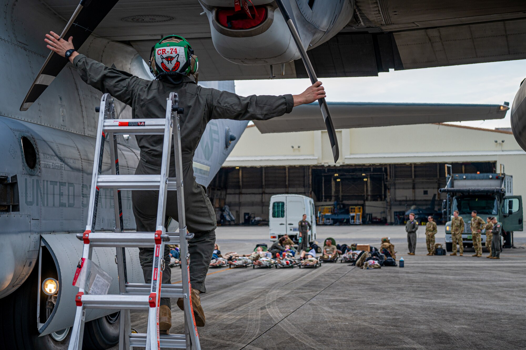 U.S. Marine Corps Cpl. Colton Houston, Marine Aerial Refueler Transport Squadron 152 loadmaster, performs preflight checks on a KC-130J Hercules while Airmen with the 18th Aeromedical Evacuation Squadron identify patients’ injuries before boarding at Kadena Air Base, Japan, Dec. 18, 2024.