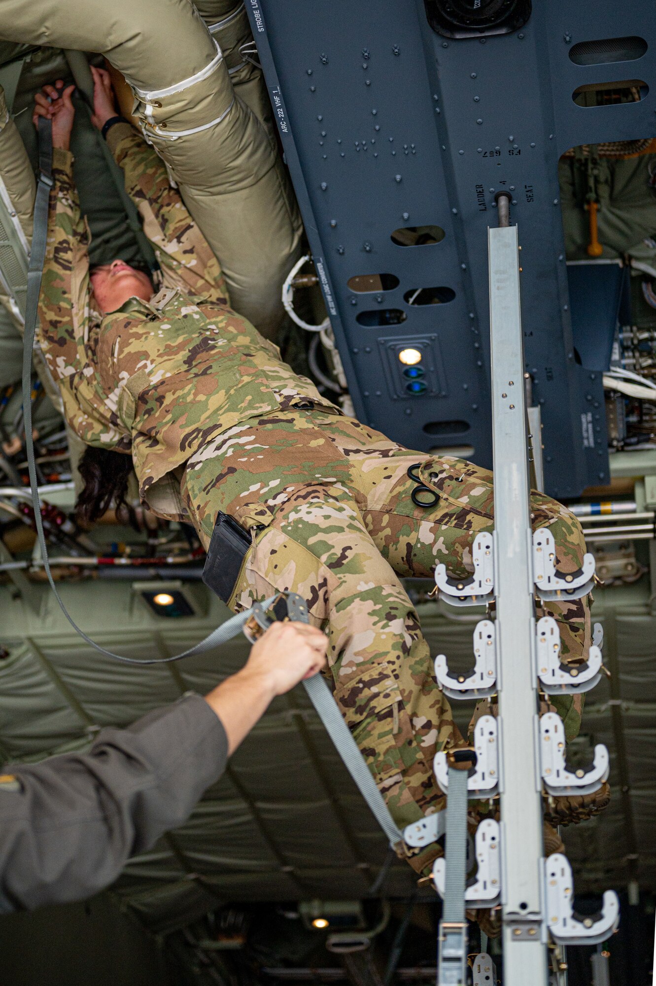 U.S. Air Force Senior Airman Jana Villaviza, 18th Aeromedical Evacuation Squadron aeromedical evacuation technician, secures straps so that simulated patients can be secured on a KC-130J Hercules during a patient transfer exercise with the Marine Aerial Refueler Transport Squadron 152 at Kadena Air Base, Japan, Dec. 18, 2024.
