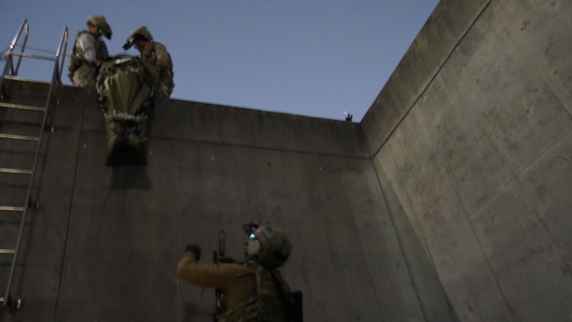 Airmen lower a casualty role player on a sled from a roof to an Airman below