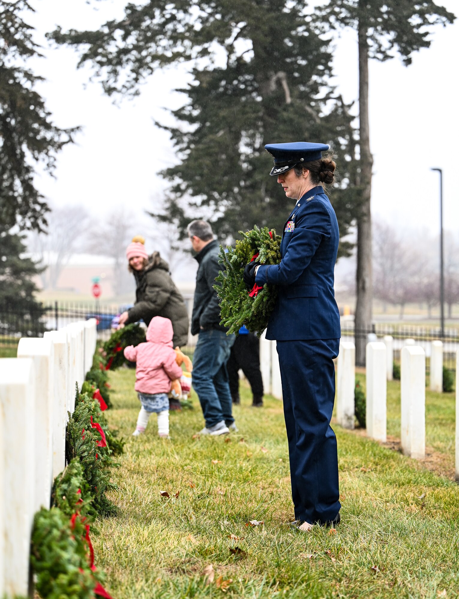 Woman lays a wreath on a headstone