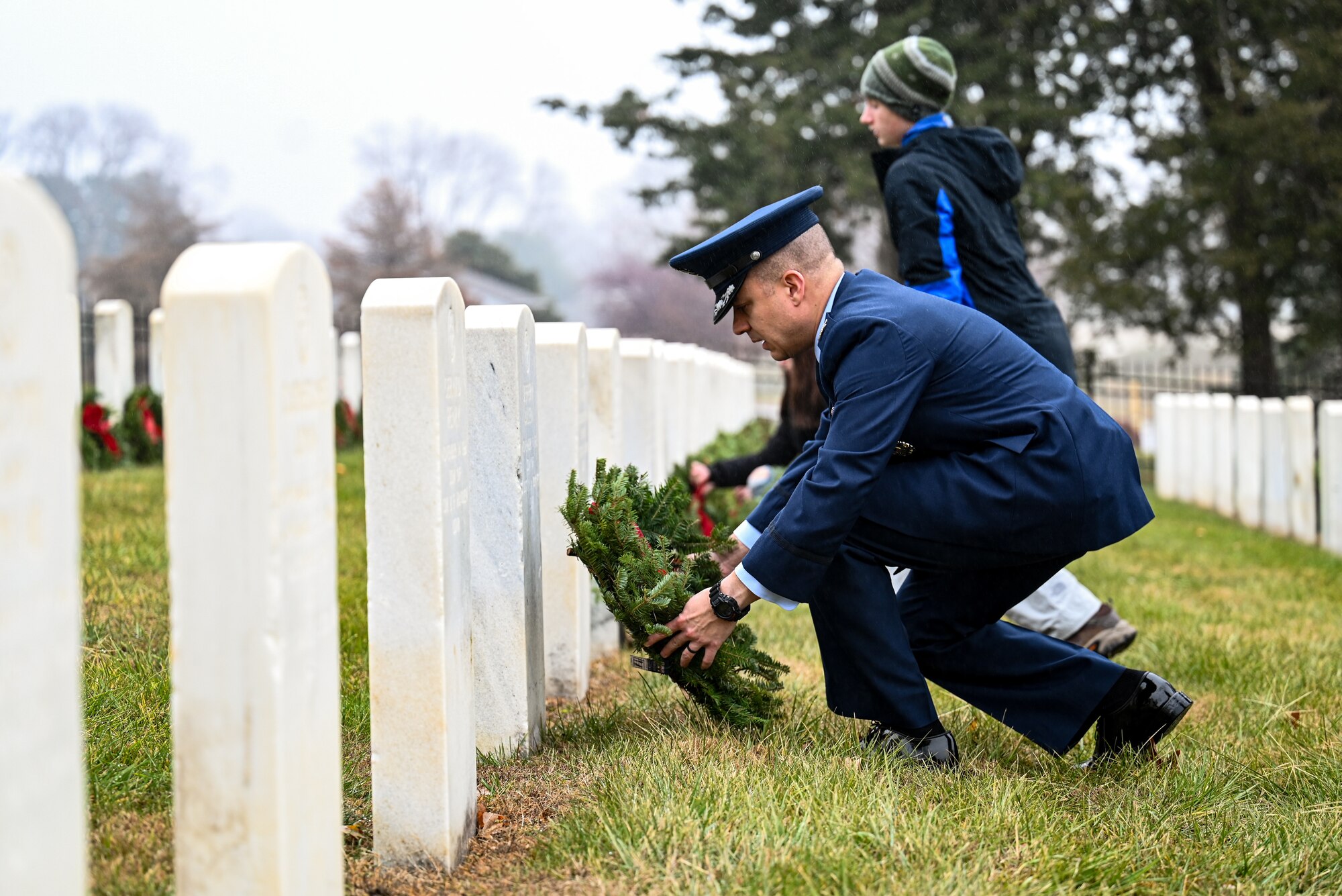 Man lays a wreath on a headstone