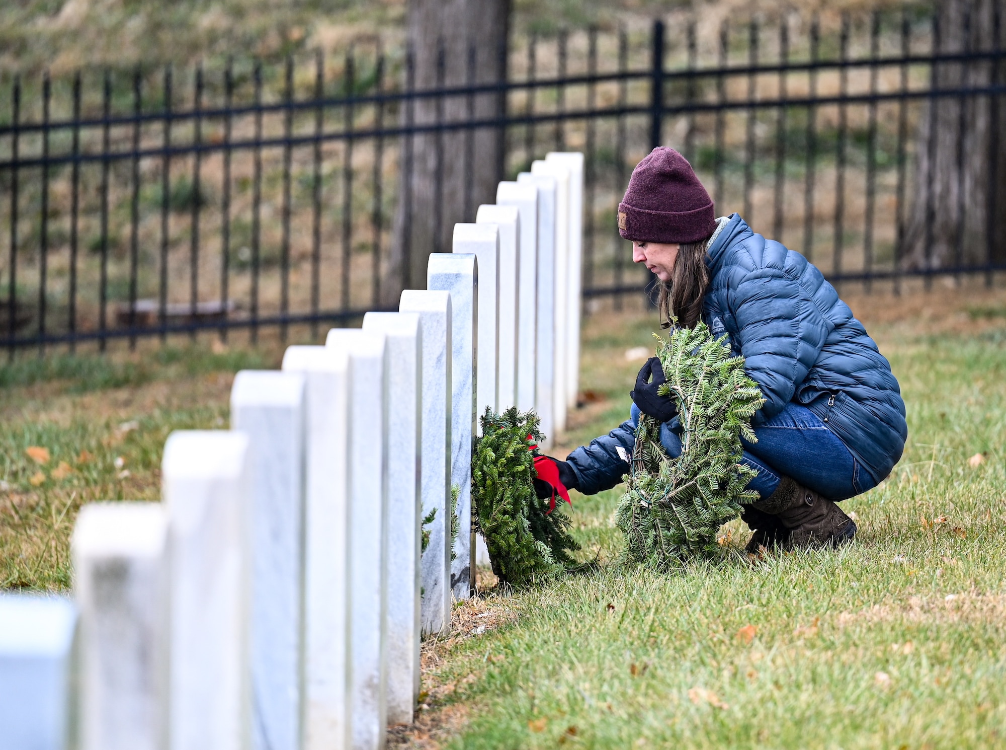 Woman lays a wreath on a headstone