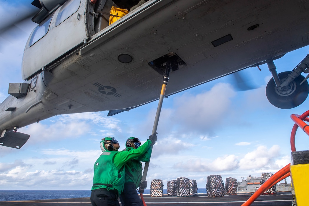 LS1 Alvin Gacad, left, and LS2 Gavin Bauer attache a cargo hook to an MH-60S Sea Hawk from HSC-4 aboard USS Carl Vinson (CVN 70) in the Philippine Sea.