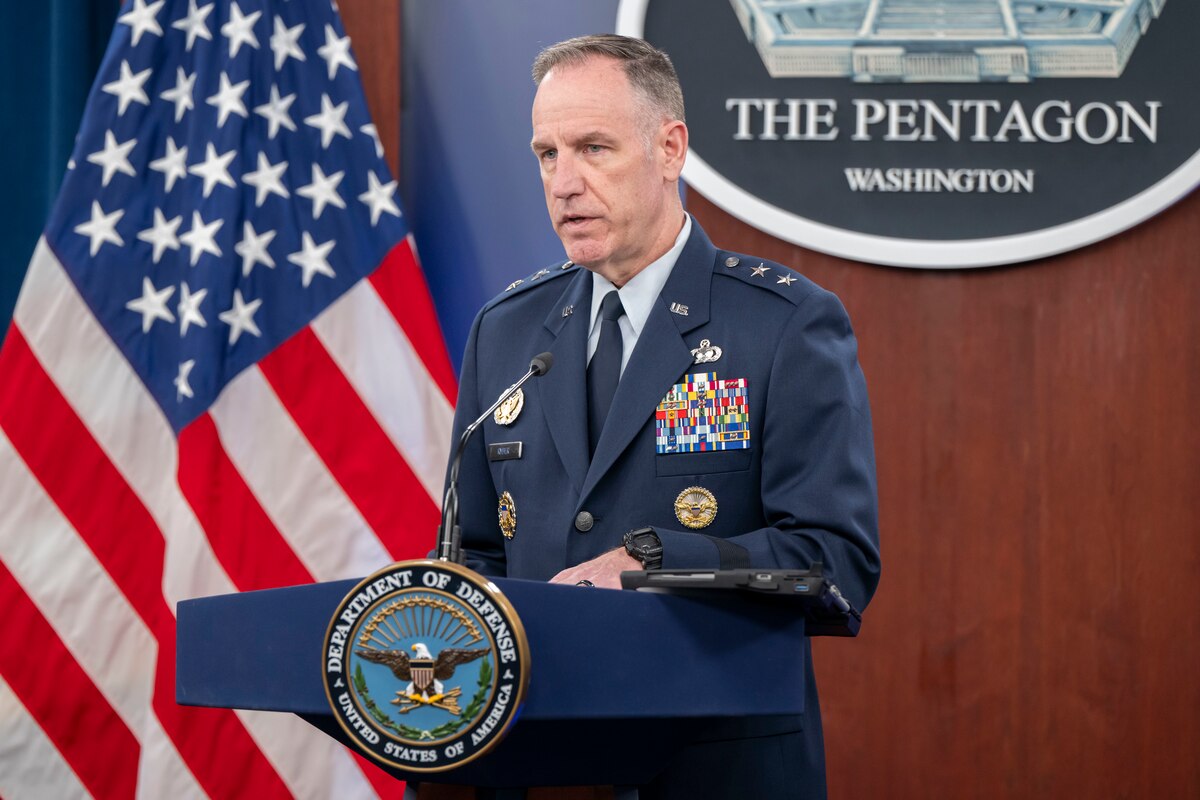 A major general stands behind a lectern saying remarks in front of the Pentagon seal and American flag.
