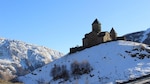 Gergeti Trinity Church on a snowy hilltop near Stepantsminda village, Georgia.